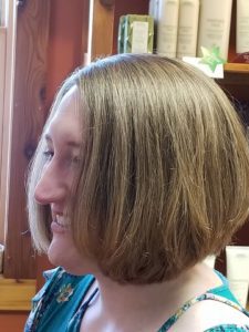 A woman smiling about her fresh haircut!